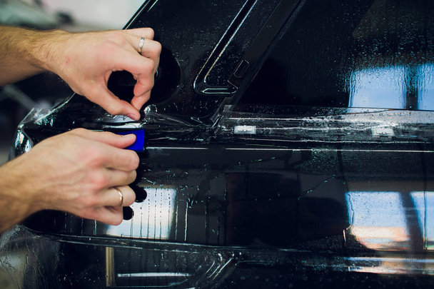 Worker hands installs car paint protection film wrap. - Zdjęcie, obraz