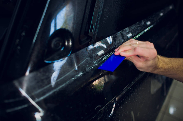 Worker hands installs car paint protection film wrap. - Fotó, kép