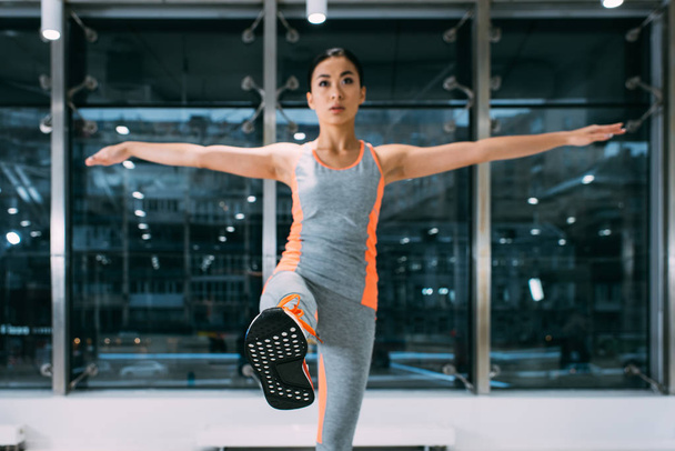 slim asian girl standing on one leg at gym - Foto, Imagem