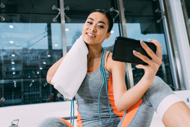 vue rapprochée de sourire asiatique sportive essuyant cou et prendre selfie à la salle de gym
 - Photo, image
