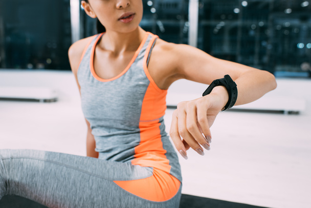 cropped view of young girl looking fitness tracker at gym - Foto, afbeelding
