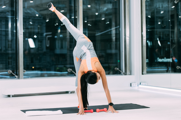karcsú lány stretching láb edzőteremben fitness szőnyeg - Fotó, kép