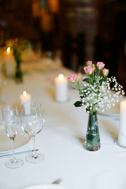 Bukiet kwiatów, płyty i świece na biały stół. - Zdjęcie, obraz