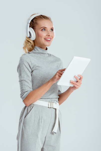 beautiful smiling woman in headphones listening music and using digital tablet isolated on grey - Φωτογραφία, εικόνα