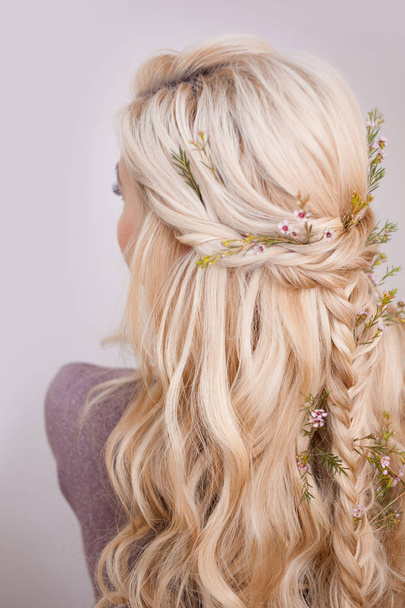 Back view of an elegant trendy hairstyle, interlacing curls and decorating with flower petals - Photo, Image