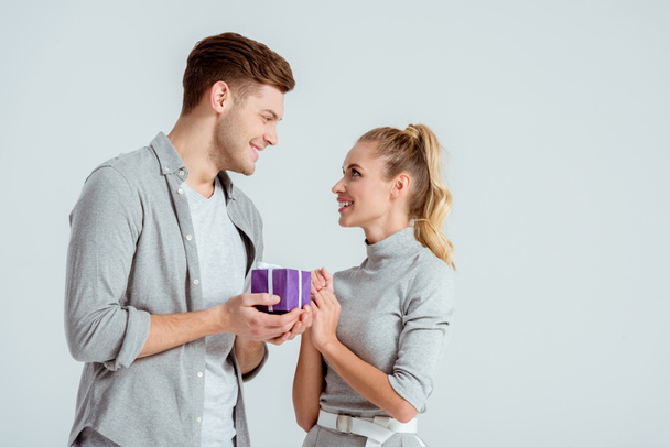 handsome man giving present to beautiful woman isolated on grey - Foto, Bild
