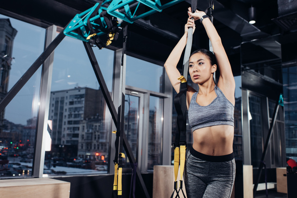 slim asian girl in sportswear training with resistance bands at modern gym - Foto, Imagem