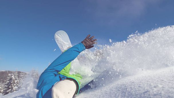 Κοντινό πλάνο: Ακραία σταυρό χώρα snowboarder κολλάει σε φρέσκο χιόνι και ξεκινά το τροχαίο κατηφόρα. Freerider σκάλισμα κάτω επικίνδυνο βουνό πέφτει σε βαθύ χιόνι. Αστεία snowboarder αποτύχει σε τέλεια ημέρα. - Φωτογραφία, εικόνα