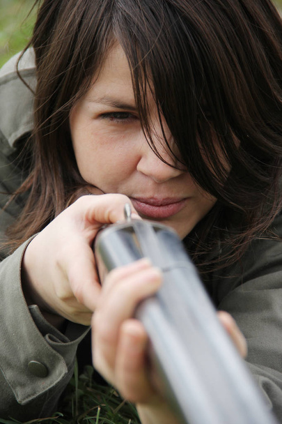 Close up de uma jovem caçadora apontando sua arma no campo
. - Foto, Imagem