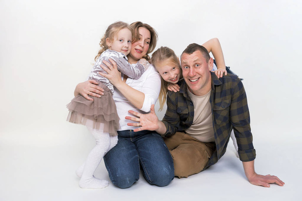 灰色の背景に笑顔幸せな家族の肖像画。2 人の子供の娘、父、笑いとハグのお母さん。家族の休日と一体感. - 写真・画像