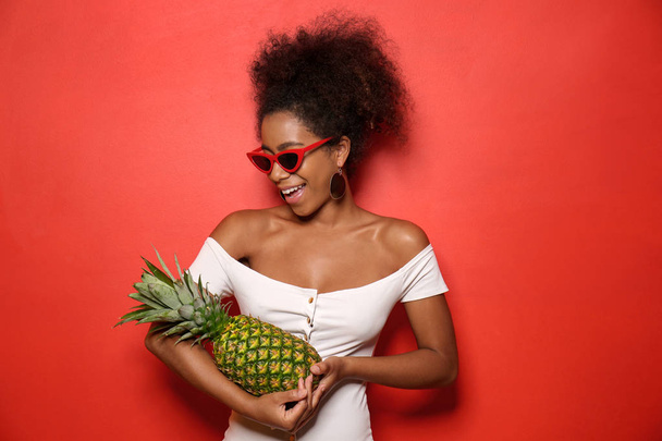 Beautiful African-American woman with pineapple on color background - Фото, изображение