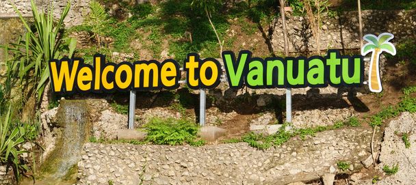 Πολύχρωμο ηλιόλουστο κίτρινο και πράσινο σημάδι καλωσορίζοντας τους τουρίστες στο όμορφο Βανουάτου. Διασκέδαση Καλώς ήρθατε στο Vanuatu υπογράψει χαιρετά ταξιδιώτες από όλο τον κόσμο. Αστείο σημάδι που δείχνει φιλοξενία. - Φωτογραφία, εικόνα