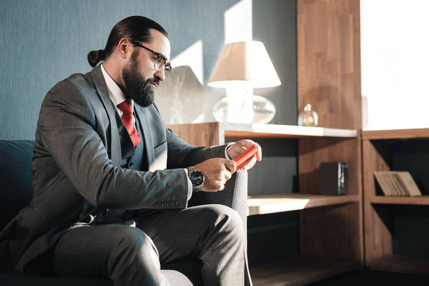 Serious bearded businessman reading e-mails on his red phone - Photo, Image