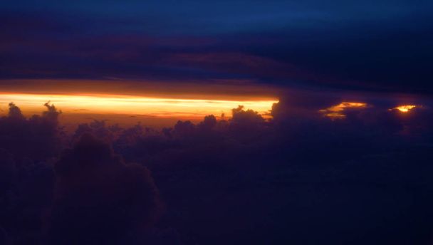Копія простору, Pov: Пишні хмари і фіолетовим небом прикриття мальовничі помаранчеві sunrise високо над землею. Захоплюючий вид з вікна літака з палена помаранчевий sunlight заглядав через щільними хмарами - Фото, зображення