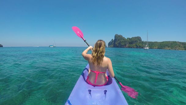 SULJE Up: Tuntematon urheilullinen nainen katselee ympärilleen henkeäsalpaava luonto, kun hän kajakit kohti kaunista trooppinen saari. Nuori valkoihoinen nainen melat noin upea Phi Phi saaret hänen viileä kajakki
 - Valokuva, kuva