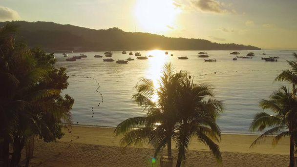 Повітряні Lens Flare: Мальовничі тропічні захід висвітлює спокійній бухті в приголомшливій острови Пхі-Пхі. Красиві золоте сонце променів блиск на спокійний піщаний пляж і човнах прив'язаний. Захоплюючий літнього вечору - Фото, зображення
