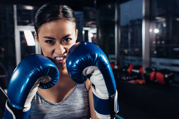 close up view of shouting girl in boxing gloves at gym - Zdjęcie, obraz