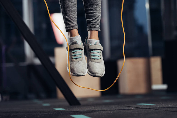 Ausgeschnittene Ansicht weiblicher Beine beim Springen mit Springseil im Fitnessstudio - Foto, Bild