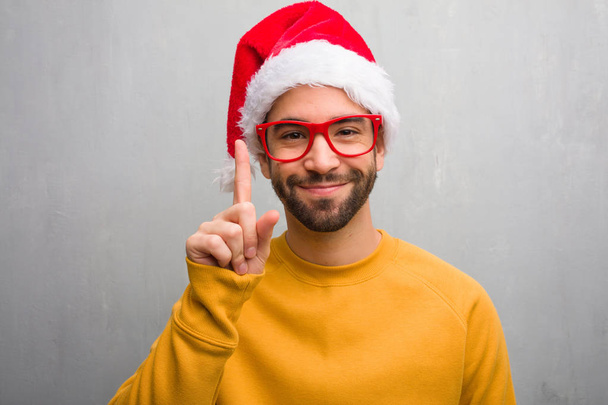 Jeune homme célébrant Noël jour tenant des cadeaux montrant numéro un
 - Photo, image
