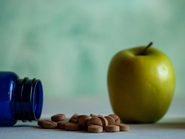 Una manzana y un recipiente azul con pastillas de fibra vegetal sobre una mesa
 - Foto, imagen