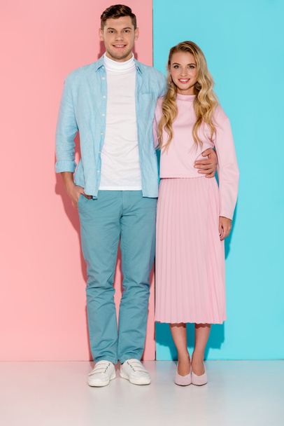 smiling couple looking at camera and posing on pink and blue background - Foto, immagini