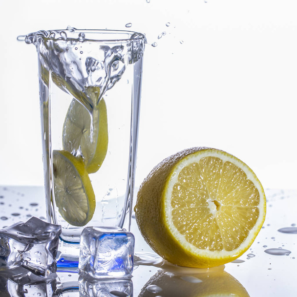 A glass of lemonade on a light background with splashing water close up - Foto, Imagen