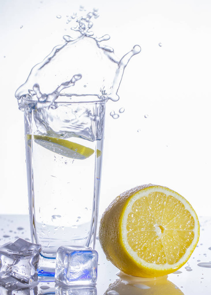A glass of lemonade on a light background with splashing water close up - Foto, Bild