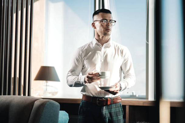 Stylish businessman wearing dark squared shirt drinking some coffee - Zdjęcie, obraz