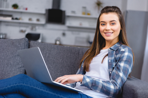 attractive happy girl using laptop and smiling at camera - Zdjęcie, obraz