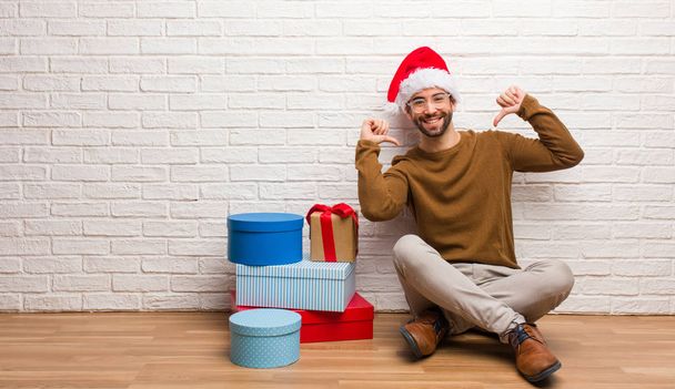 junger Mann sitzt mit Geschenken und feiert Weihnachten mit erhobenem Zeigefinger, Beispiel zu folgen - Foto, Bild
