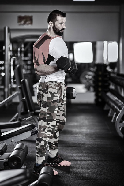 Man with dumbbells in the gym, working out - Photo, image