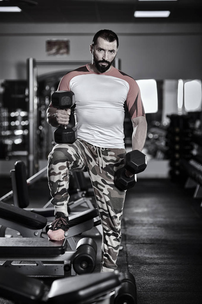 Man with dumbbells in the gym, working out - Photo, image