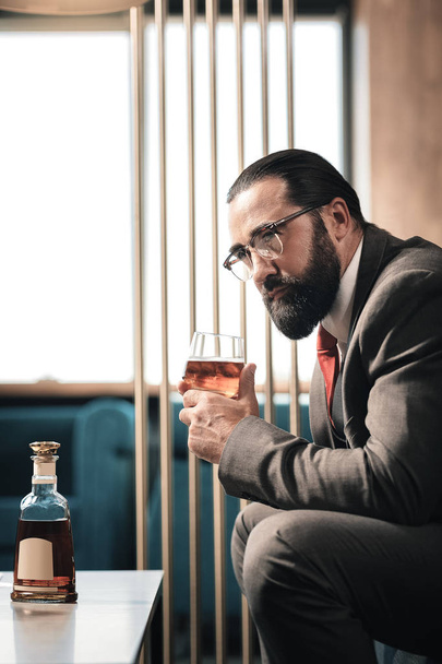 Mature businessman feeling tired after work and drinking alcohol - Zdjęcie, obraz