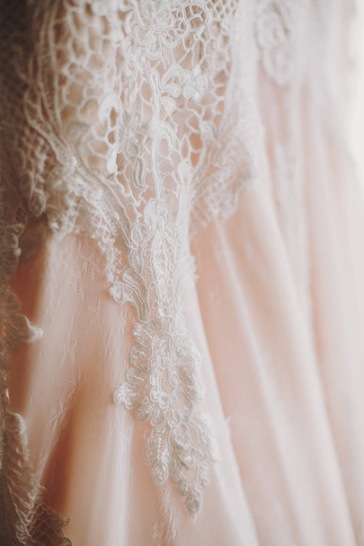 豪華な近代的なウェディング ドレスは、ウィンドウにぶら下がっています。レース花の詳細、パステル調のピンク色で驚くほどスタイリッシュな結婚式のガウン。ウエディング サロン - 写真・画像
