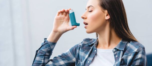 girl using inhaler while suffering from asthma at home  - Foto, Imagen