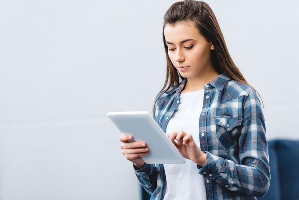 menina bonita em camisa quadriculada usando tablet digital em casa
 - Foto, Imagem