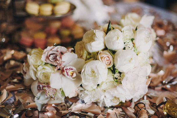Стильные свадебные букеты с белыми розами, пионом и орхидеями на столе с золотыми конфетти. Современные цветочные украшения
 - Фото, изображение