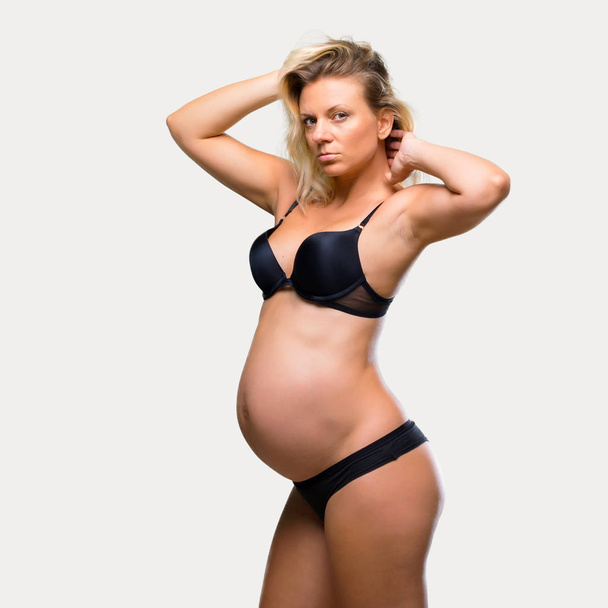 Blonde těhotná žena v prádle na izolované šedé pozadí - Fotografie, Obrázek