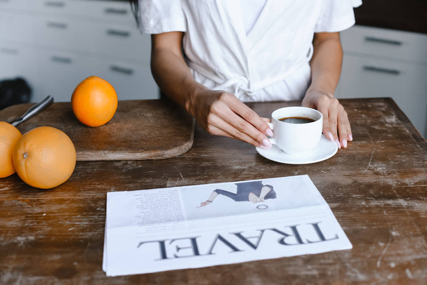 обрізане зображення змішаної гонки дівчини в білому халаті, що приймає чашку кави вранці на кухні
 - Фото, зображення