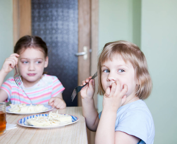 μικρό κορίτσι συνεδρίαση στην κουζίνα και να τρώτε ομελέτα - Φωτογραφία, εικόνα