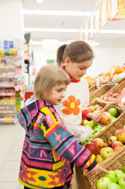 Petites filles choisissant des produits au supermarché
.  - Photo, image