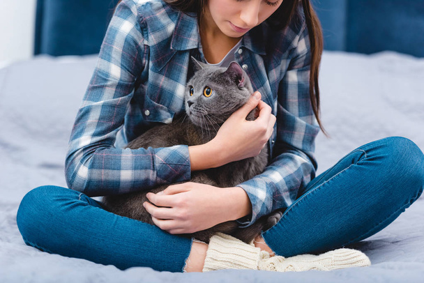 Schnappschuss einer jungen Frau, die mit entzückender grauer Katze auf dem Bett sitzt  - Foto, Bild
