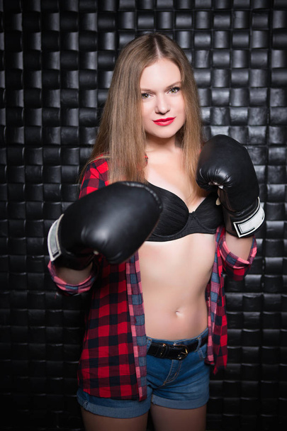 Bella donna bionda in posa in camicia a scacchi sbottonata con guanti da boxe
 - Foto, immagini