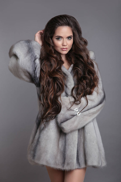 Elegant woman in mink fur coat isolated on gray studio background. Brunette Girl in Luxury Winter outerwear. - Photo, Image