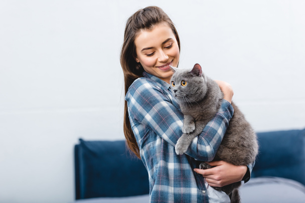 smiling young woman holding cute british shorthair cat - Фото, изображение
