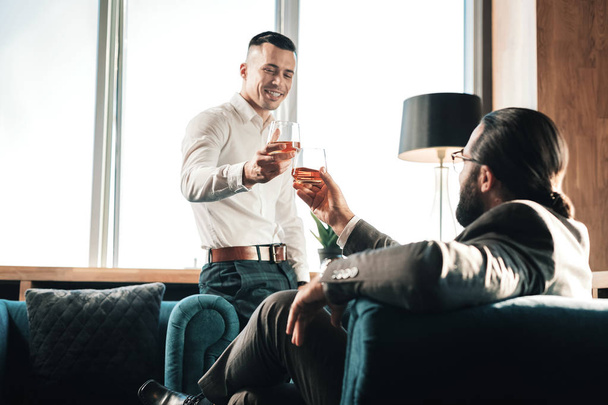 Young man drinking some whisky with his business partner - Foto, Imagem