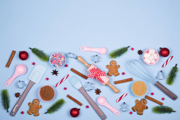 クリスマスのベーキングの背景。クリスマスのクッキー、台所用品、青のパステル調の背景にジンジャーブレッド クッキーを料理の食材。クリスマス装飾的なボーダーお祭り要素のコピー スペース平面図. - 写真・画像