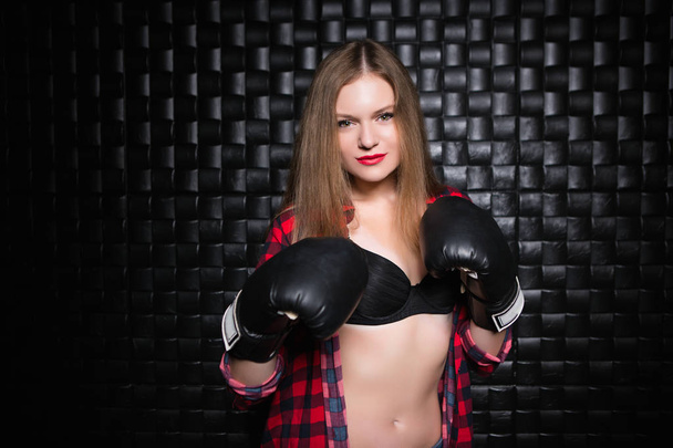 Portrait of serious young blonde woman posing in checkered shirt and boxing gloves - Foto, imagen