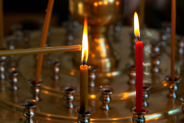 Свеча подожжена. Свечи горят в церкви на специальном стенде с люстрами
. - Фото, изображение