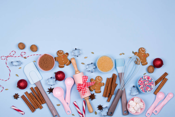 Ψήσιμο Χριστουγέννων μπισκότα κάρτα. Χριστούγεννα μπαχαρικά, κόπτες μπισκότων, συστατικά για ψήσιμο και κουζίνα σκεύη μελόψωμο μπισκότα Χριστουγέννων σε μπλε παστέλ φόντο  - Φωτογραφία, εικόνα
